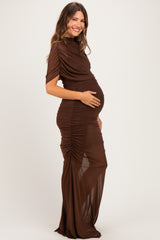 woman wearing a brown ruched maternity dress with short sleeves and a slit, gently holding her baby bump