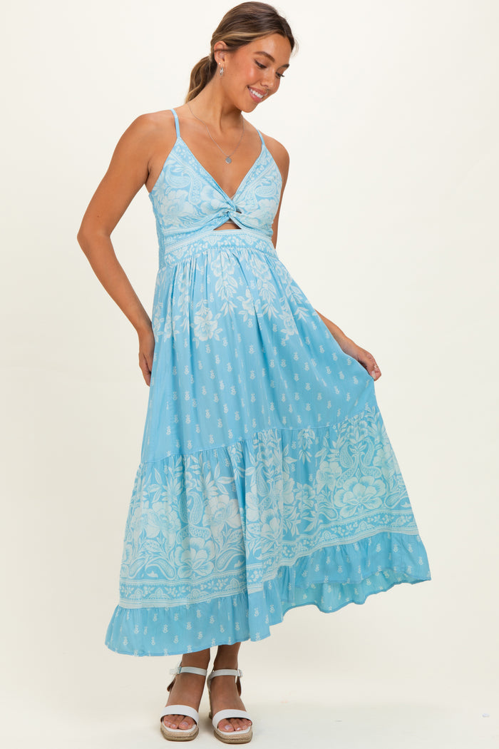 woman wearing a light blue maternity maxi dress with a cutout and floral design, showing her baby bump
