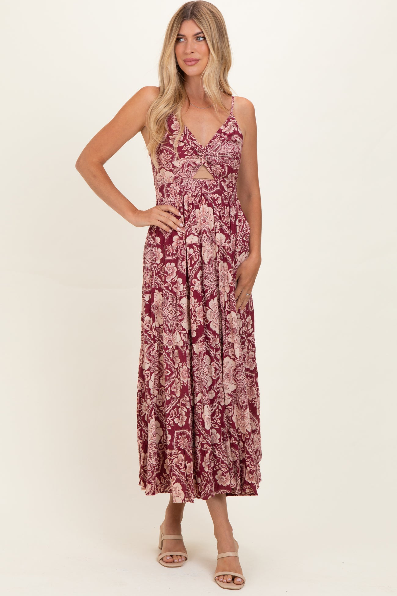 woman wearing a burgundy floral maxi dress with a v-neckline and cutout detailing, standing pose