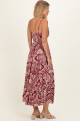 woman wearing a red floral maxi dress with adjustable straps and a smocked back, standing sideways