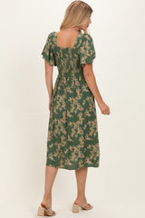 woman wearing a green floral midi dress with short flutter sleeves and a smocked back, shown from the back