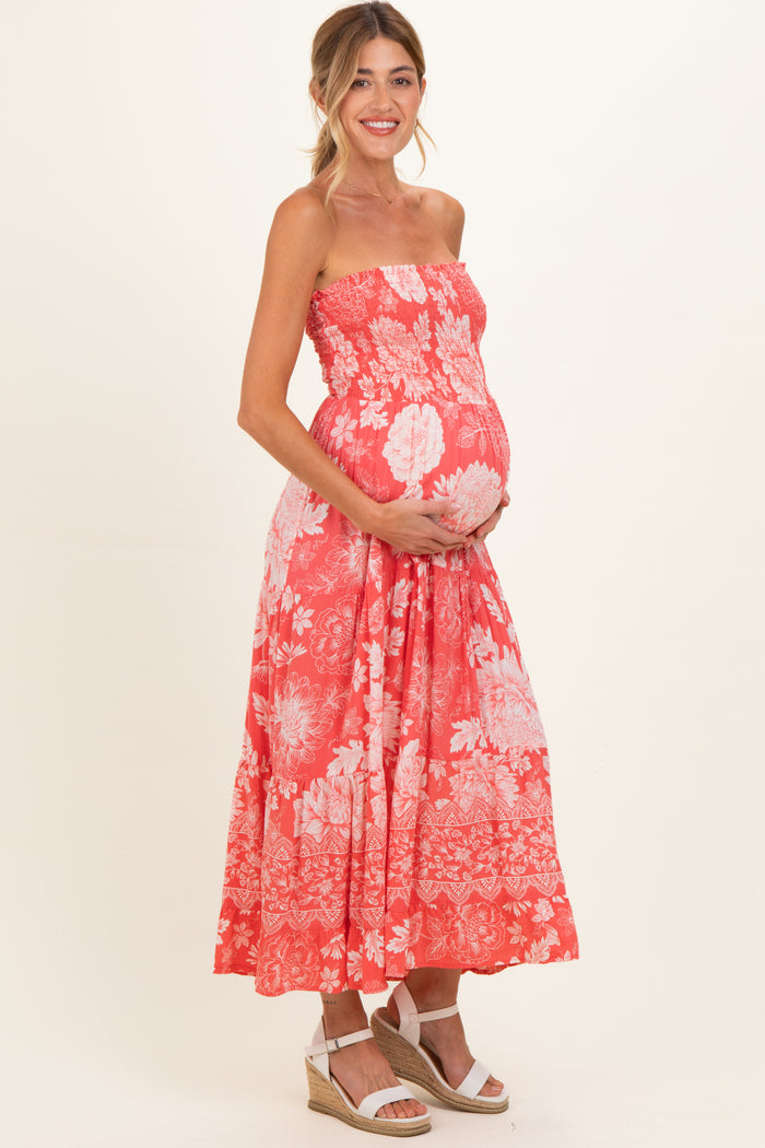 woman wearing a coral strapless maternity dress with floral print and holding her baby bump