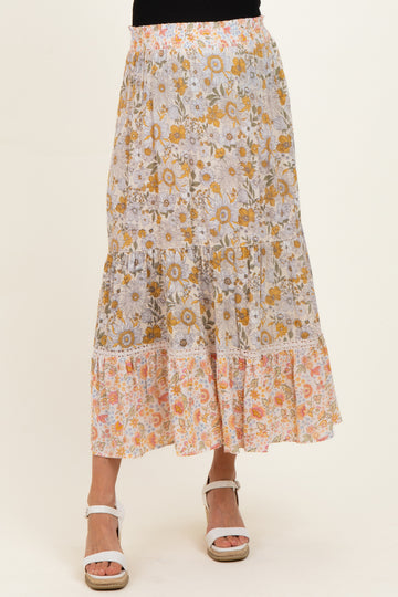 woman wearing a floral maternity maxi skirt with tiers in yellow and orange hues
