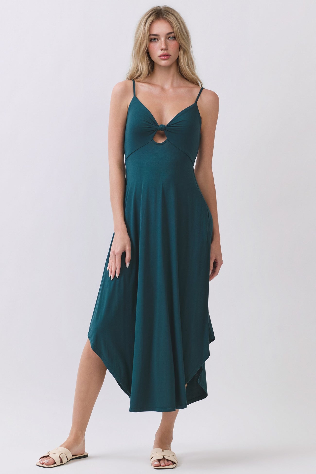 woman wearing a teal sleeveless maxi dress with a front twist detail and uneven hemline