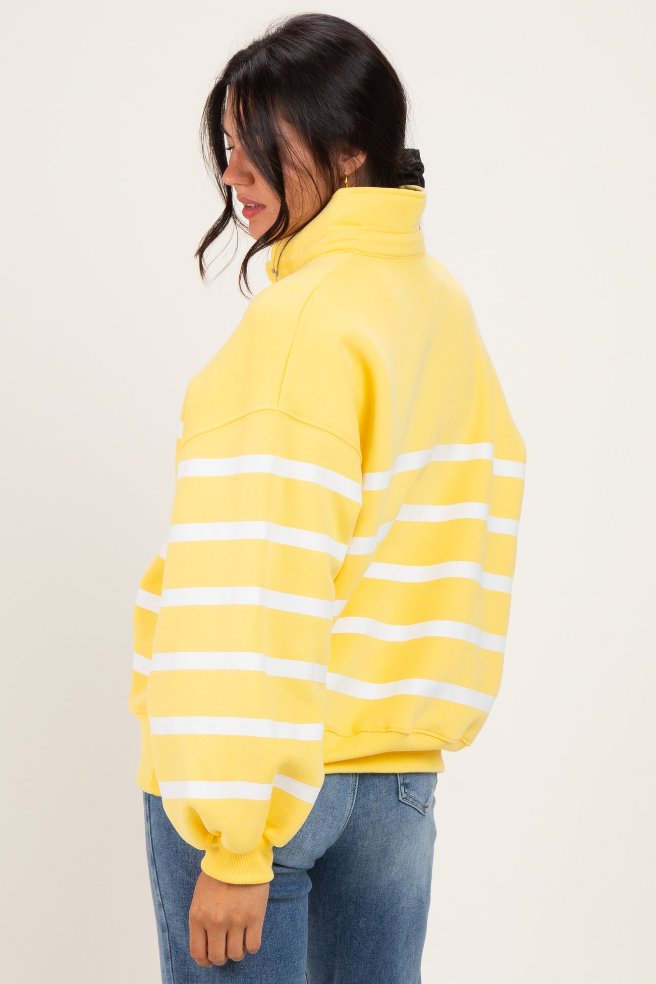 woman wearing a yellow and white striped oversized sweatshirt with a high collar and relaxed fit