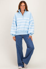 woman wearing a light blue striped oversized sweatshirt with a buttoned collar and wide-leg jeans