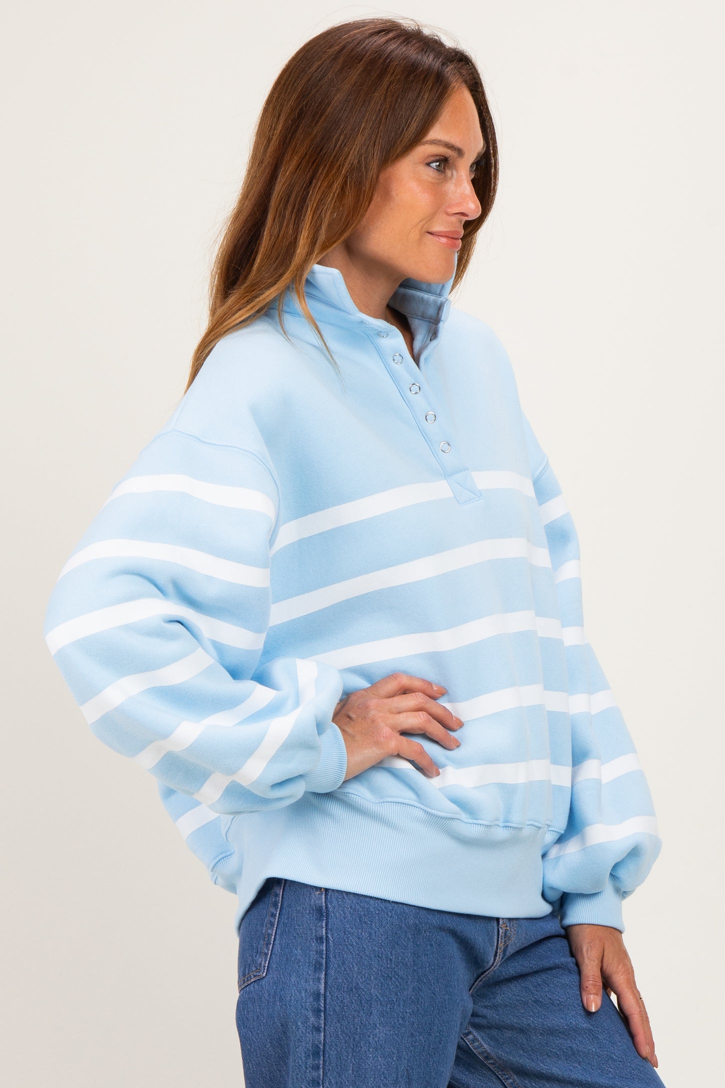 woman wearing a light blue striped pullover sweatshirt with a collar and buttons, styled with high-waisted jeans