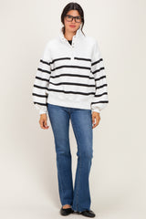 woman wearing a white and black striped pullover with a collar, paired with flared jeans and black flats