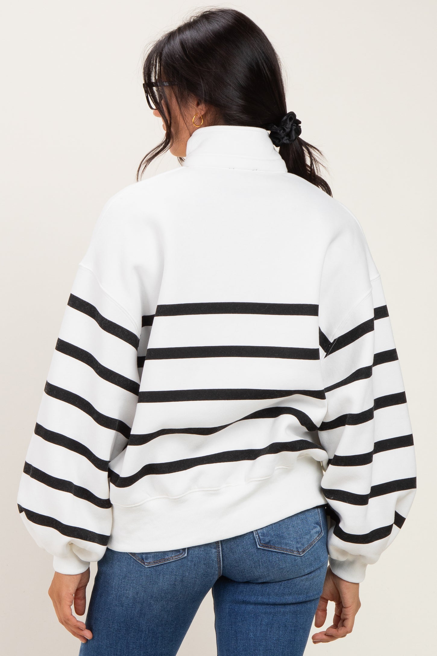 woman wearing a white and black striped oversized sweatshirt with a high collar and balloon sleeves