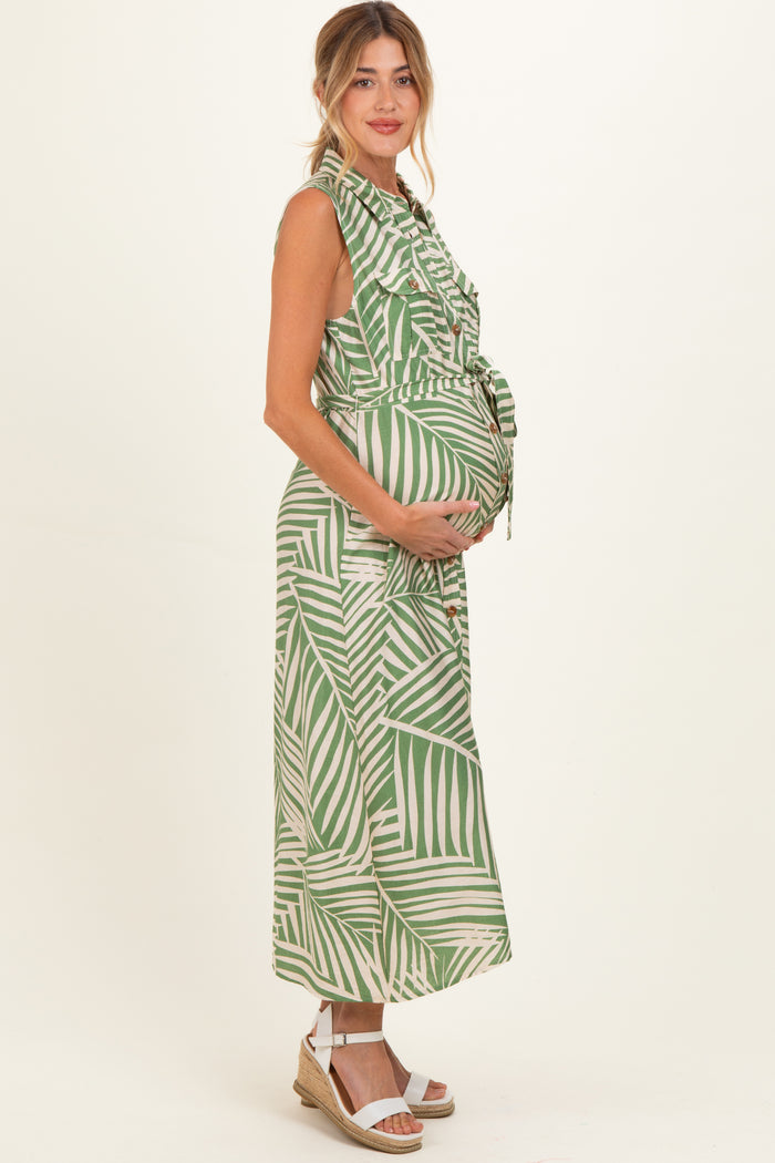 woman wearing a green and white tropical print maternity dress and holding her baby bump