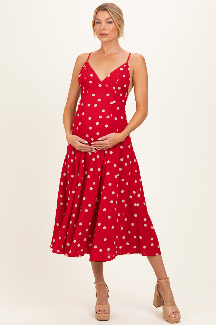 woman wearing a red polka dot maternity dress and holding her baby bump