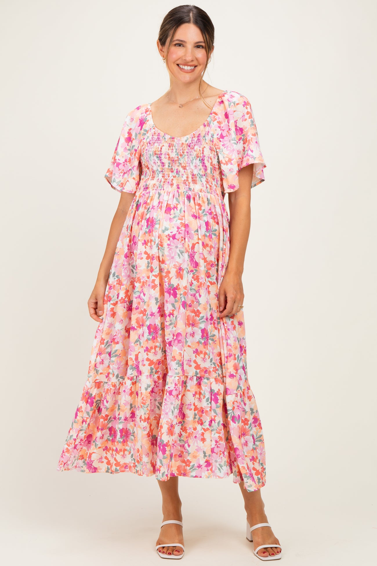 woman wearing a pink floral maternity maxi dress with short flutter sleeves and a smocked bodice