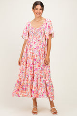 woman wearing a pink floral maternity maxi dress with short flutter sleeves and a smocked bodice