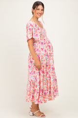 woman wearing a floral pink maternity maxi dress and showing her baby bump