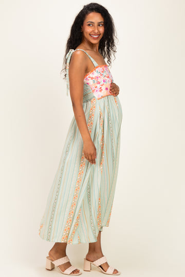 woman wearing a floral print maternity maxi dress with a smocked bodice and straps, showing her baby bump