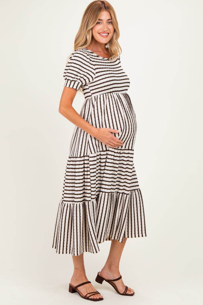 woman wearing a striped tiered maternity dress, showing her baby bump, styled with short sleeves and a relaxed fit