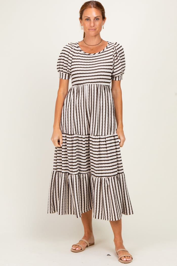 woman wearing a black and cream striped tiered midi dress with puff sleeves and a round neckline