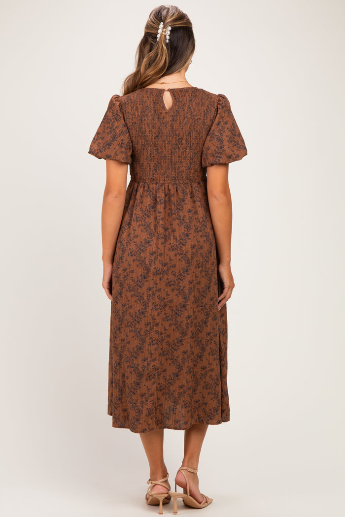woman wearing a brown floral print maternity dress with puff sleeves and a keyhole back detail