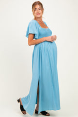 woman wearing a light blue maternity maxi dress with a smocked bodice and flutter sleeves, showing her baby bump