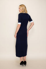 woman wearing a navy blue midi dress with fitted silhouette and white cuff details, shown from the back