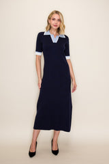 woman wearing a navy midi dress with a light blue polo collar and short sleeves, standing in black high heels