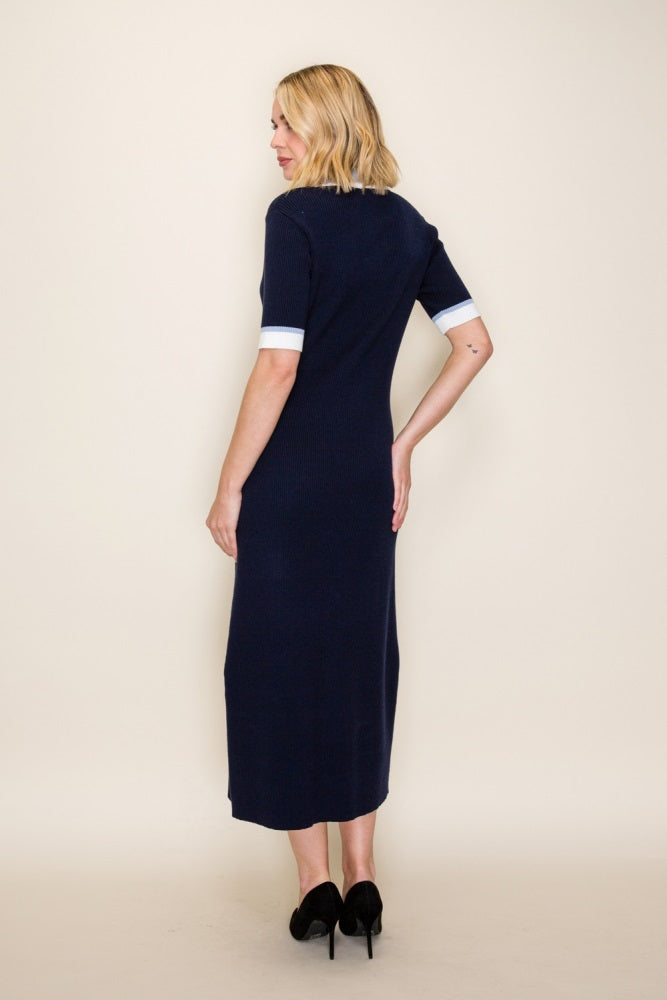 woman wearing a navy blue midi dress with fitted silhouette and white cuff details, shown from the back