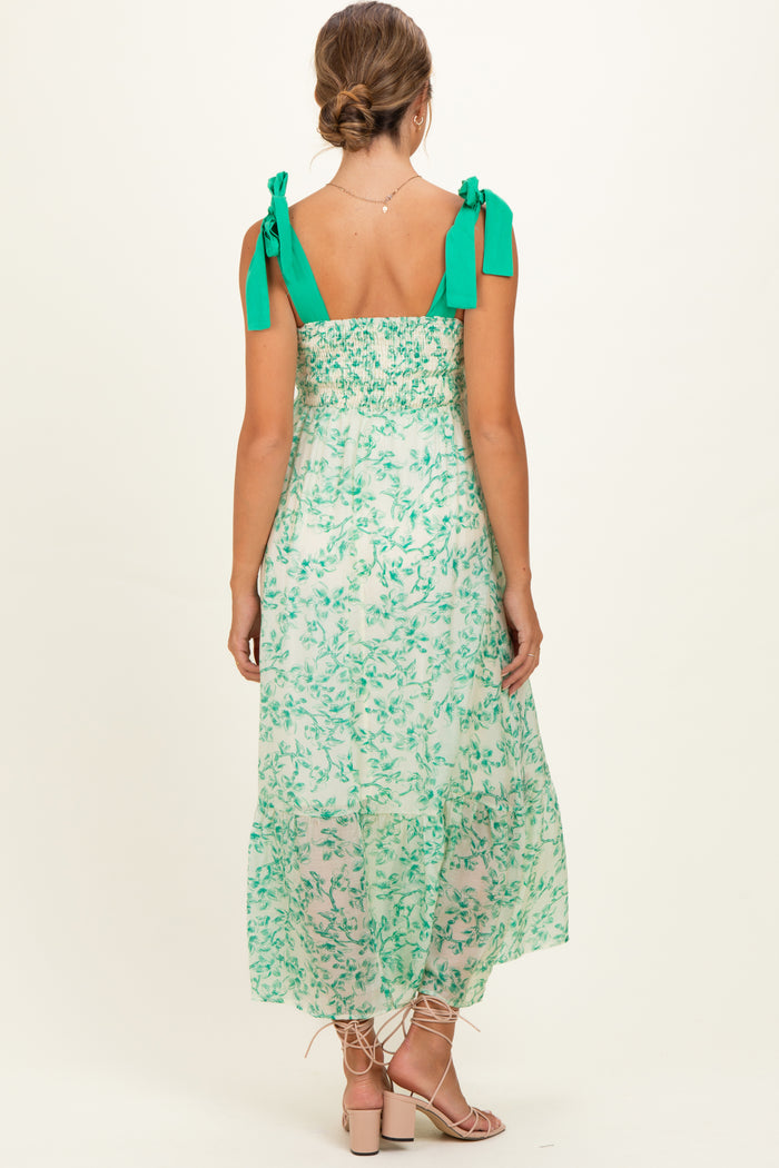woman wearing a green floral maternity maxi dress with tie straps and a smocked back.