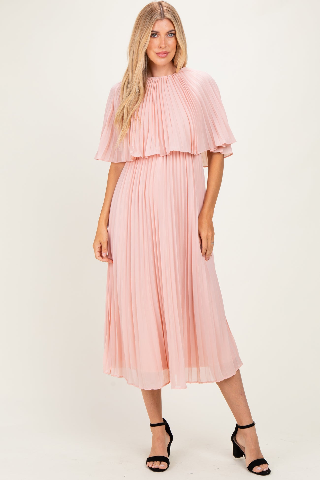 woman wearing a blush pink pleated midi dress with flutter sleeves and a flowy silhouette