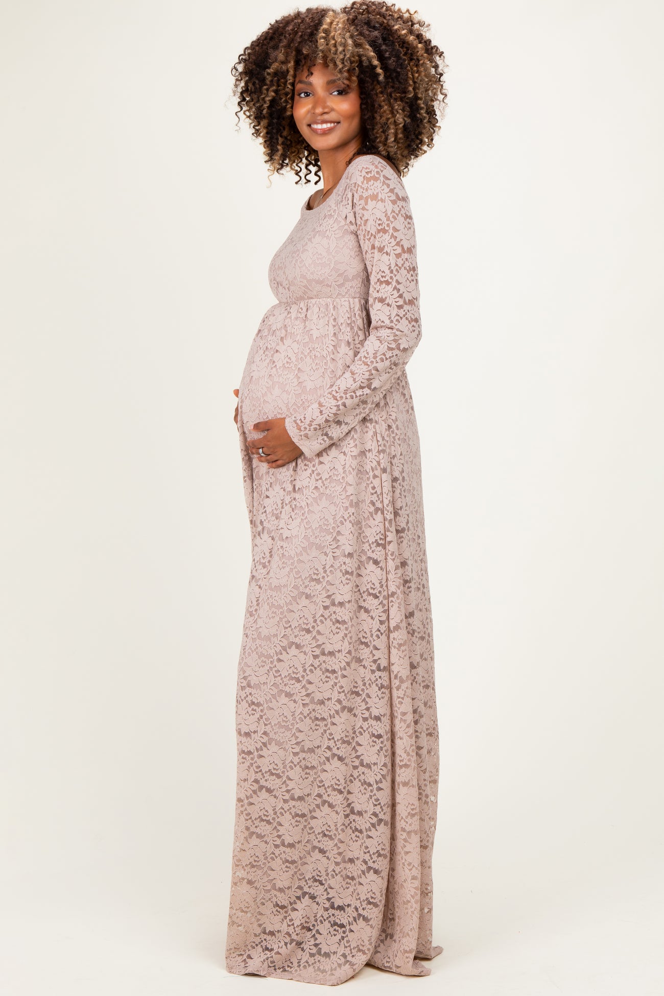 woman wearing a long sleeve pink lace maternity gown and holding her baby bump