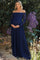 woman wearing a navy blue off-the-shoulder lace maternity gown and holding her baby bump among purple flowers