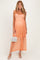 woman wearing a light orange lace maternity maxi dress with spaghetti straps and holding a white handbag, showcasing her baby bump