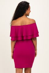 woman wearing a vibrant pink off-the-shoulder maternity dress with layered ruffles and a fitted silhouette