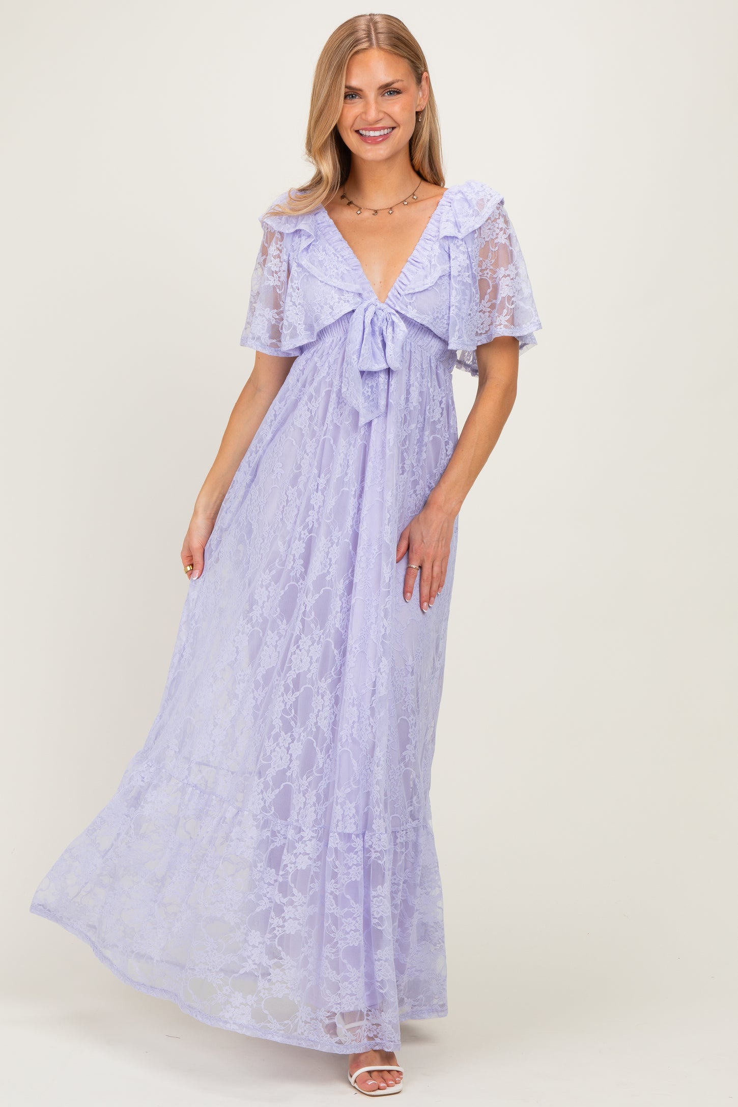 woman wearing a lavender lace maxi dress with short flutter sleeves and a tied front detail