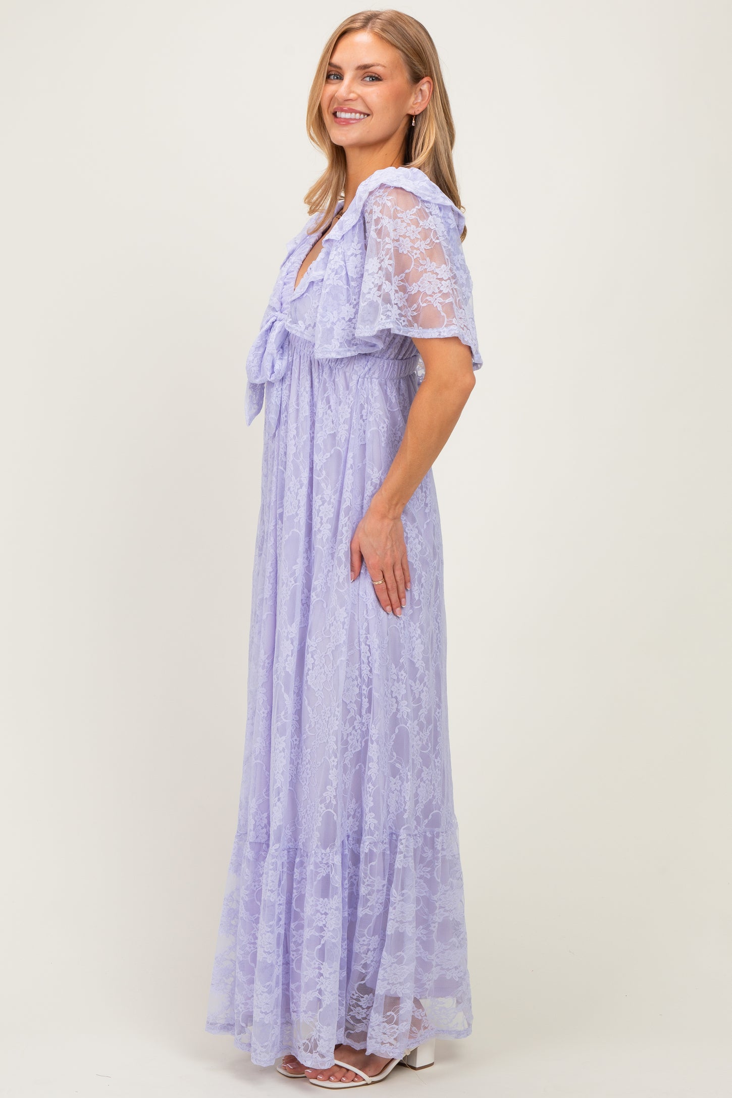 woman wearing a light purple lace maxi dress with short sleeves and a tie detail at the neckline