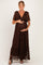 woman wearing a brown lace maternity maxi dress with ruffled sleeves and a bow detail, holding her baby bump