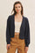woman wearing a navy blue cropped cardigan over a beige top and styled with brown high-waisted trousers
