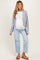 woman wearing a light gray maternity cardigan over a white tank top and blue distressed maternity jeans, showing a baby bump