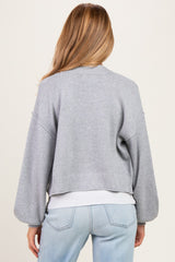 woman wearing a light gray cropped maternity cardigan with balloon sleeves, from the back