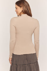 woman wearing a beige long sleeve fitted top with a high neckline, seen from the back
