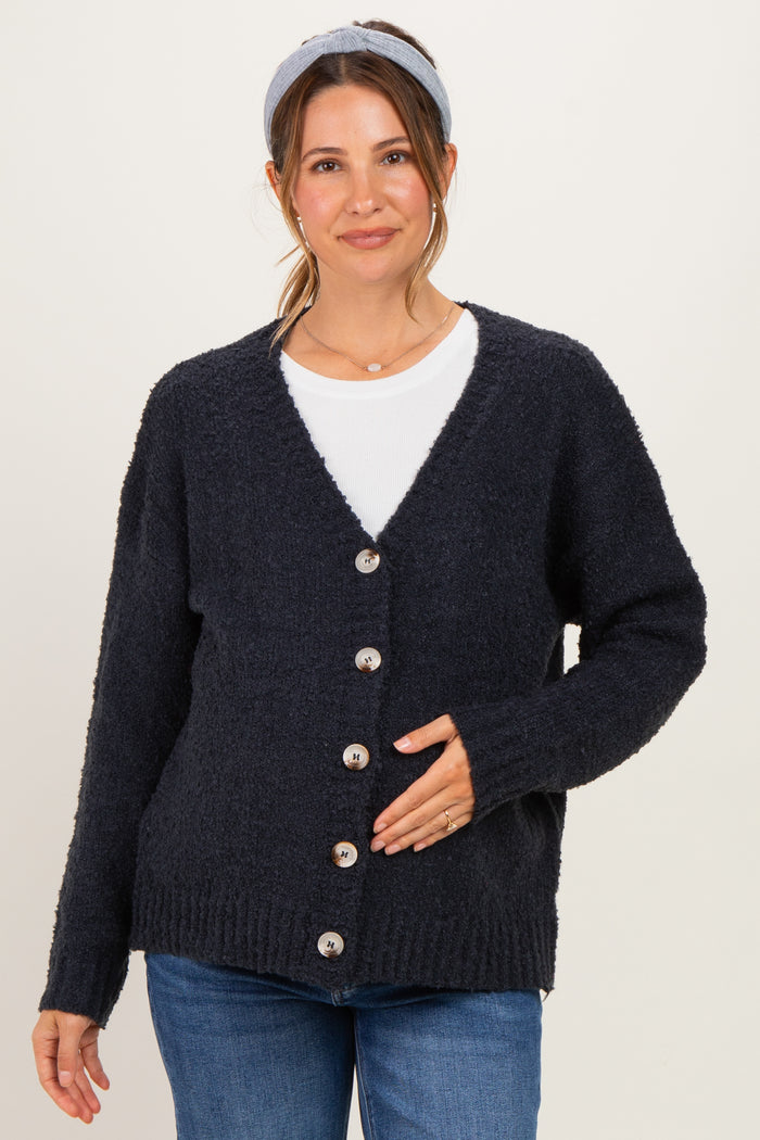 woman wearing a navy blue maternity cardigan with buttons, styled over a white shirt and holding her baby bump
