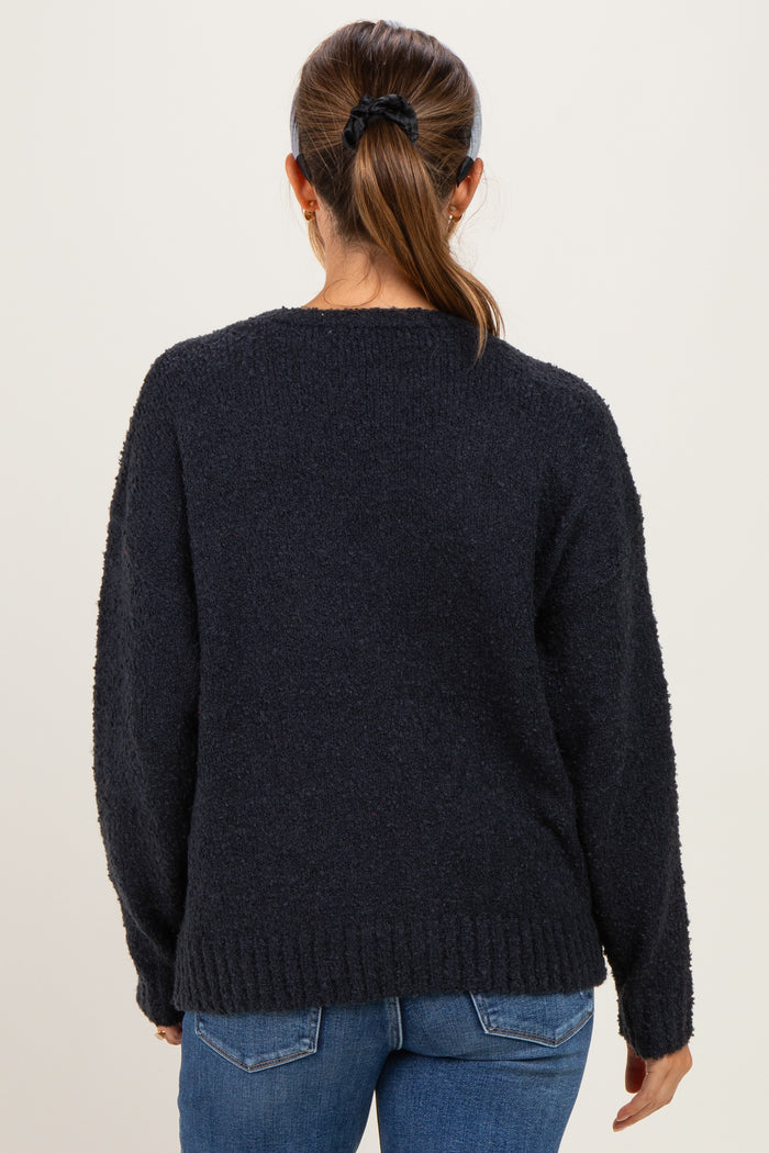 woman wearing a dark grey maternity sweater with a relaxed fit and long sleeves, styled with blue jeans