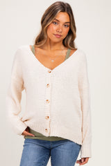woman wearing a cream button-up maternity cardigan over a green tank top with a relaxed fit and long sleeves