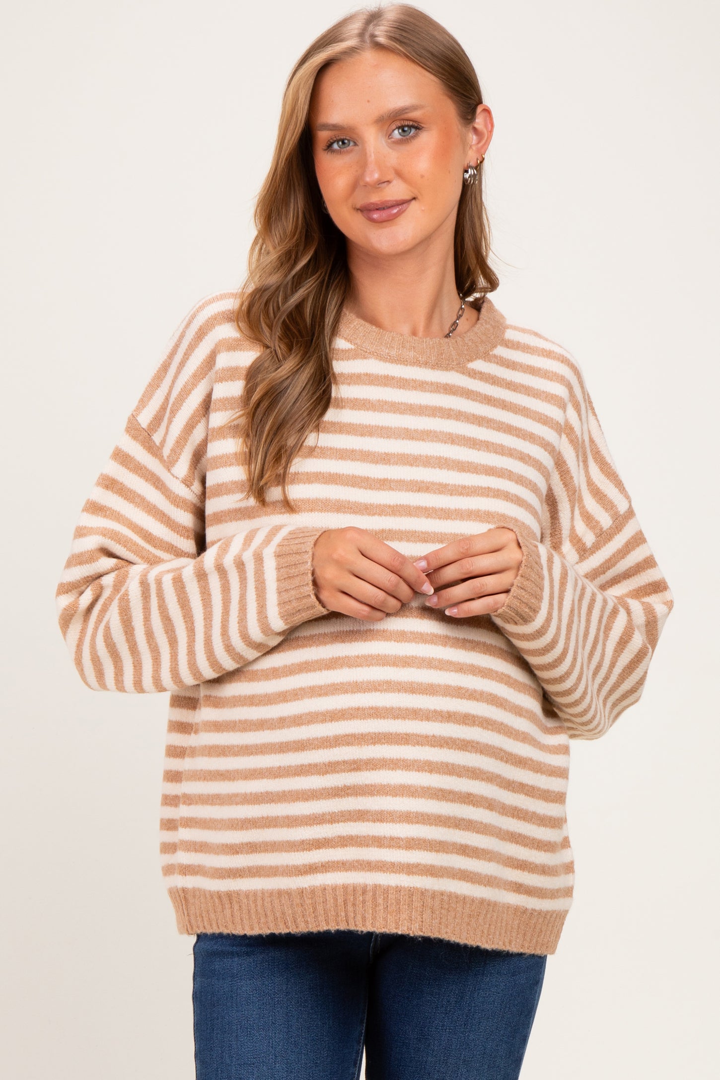 woman wearing a beige and white striped maternity sweater with a relaxed fit and long sleeves