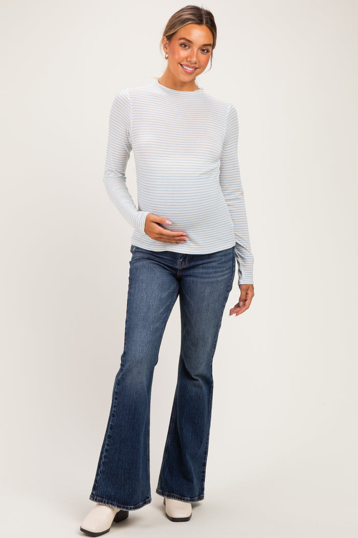 woman wearing a light blue and white striped long sleeve maternity top and holding her baby bump, paired with flared jeans