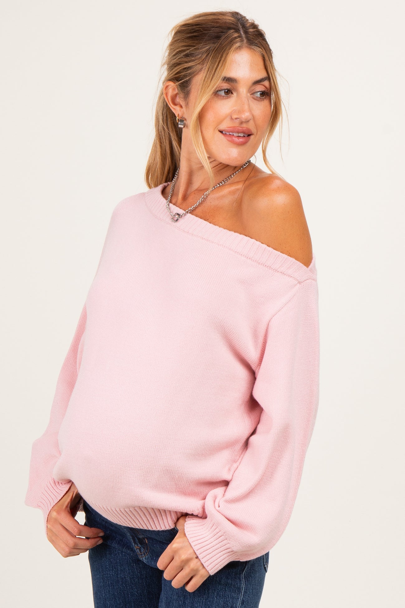 woman wearing a light pink off-shoulder maternity sweater with balloon sleeves and baby bump visible