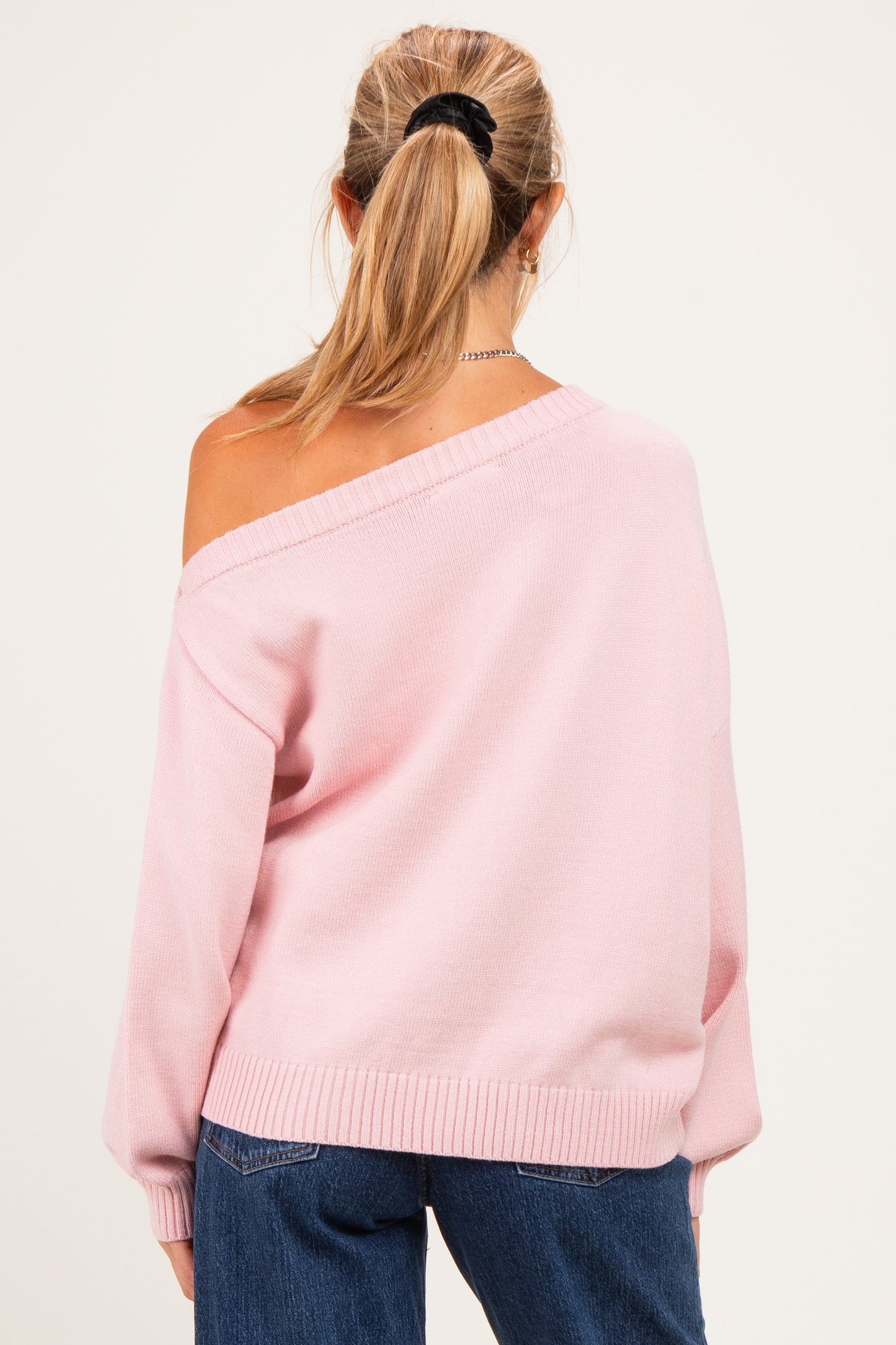 woman wearing a light pink off-shoulder maternity sweater with relaxed fit and long sleeves