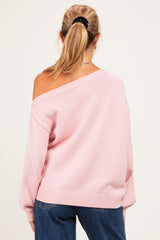 woman wearing a light pink off-shoulder maternity sweater with relaxed fit and long sleeves