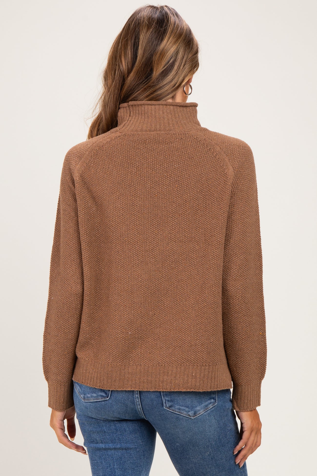 woman wearing a brown maternity sweater with a high neck and long sleeves, shown from the back