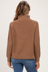 woman wearing a brown maternity sweater with a high neck and long sleeves, shown from the back
