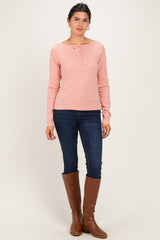 woman wearing a pink and white striped long sleeve henley top with button details and blue skinny jeans, standing in tall brown boots